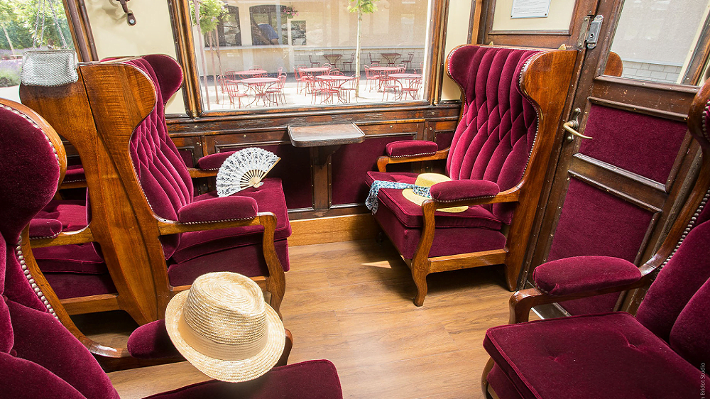 Intérieur vintage du Train de l’Ardèche – wagon historique restauré Sièges en velours rouge et bois sculpté dans un wagon historique du Train de l’Ardèche