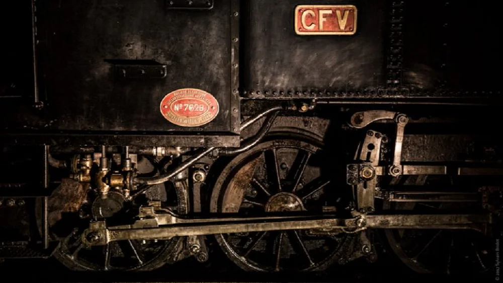 Gros plan sur les roues et la mécanique de la locomotive à vapeur du Train de l’Ardèche