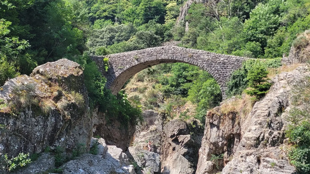 Le Pont du Diable à Thueyts : entre rivière, pierre et légende Le Pont du Diable en Ardèche vu de profil, à Thueyts, traversant une gorge encaissée bordée de végétation