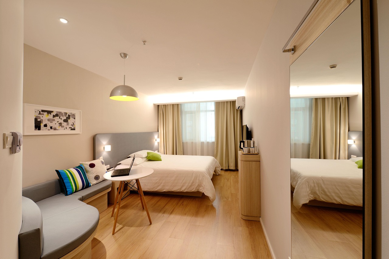 Chambre d’hôtel contemporaine avec lit double, bureau et canapé, utilisée pour comparer hôtel ou chambre d'hôtes dans le choix d’un séjour.