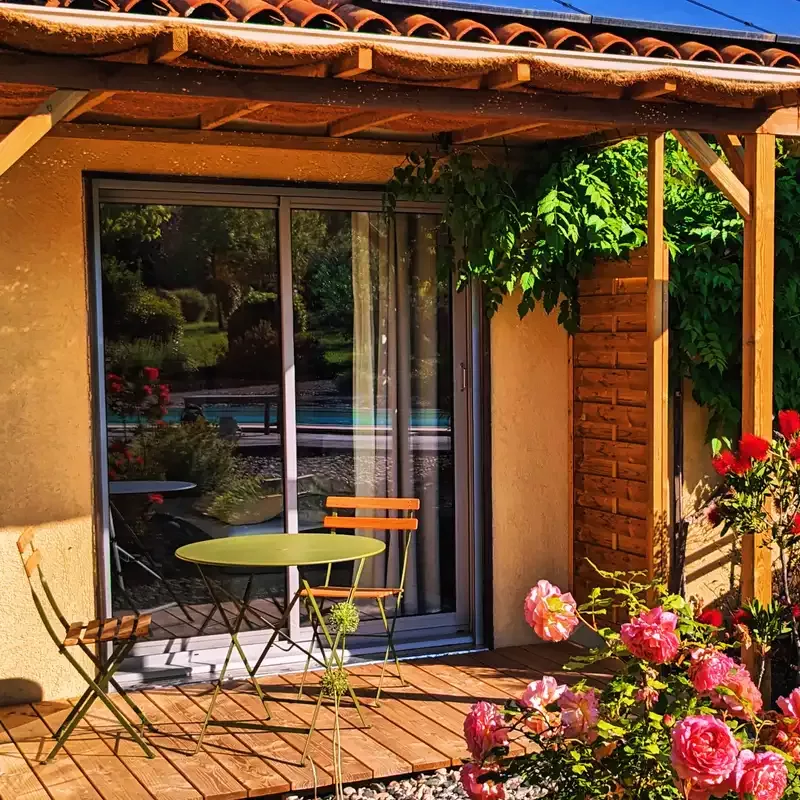Terrasse privative en bois avec table et chaises pour l'une de nos chambres d'hôtes en Ardèche, offrant un accès direct au jardin et à la piscine.
